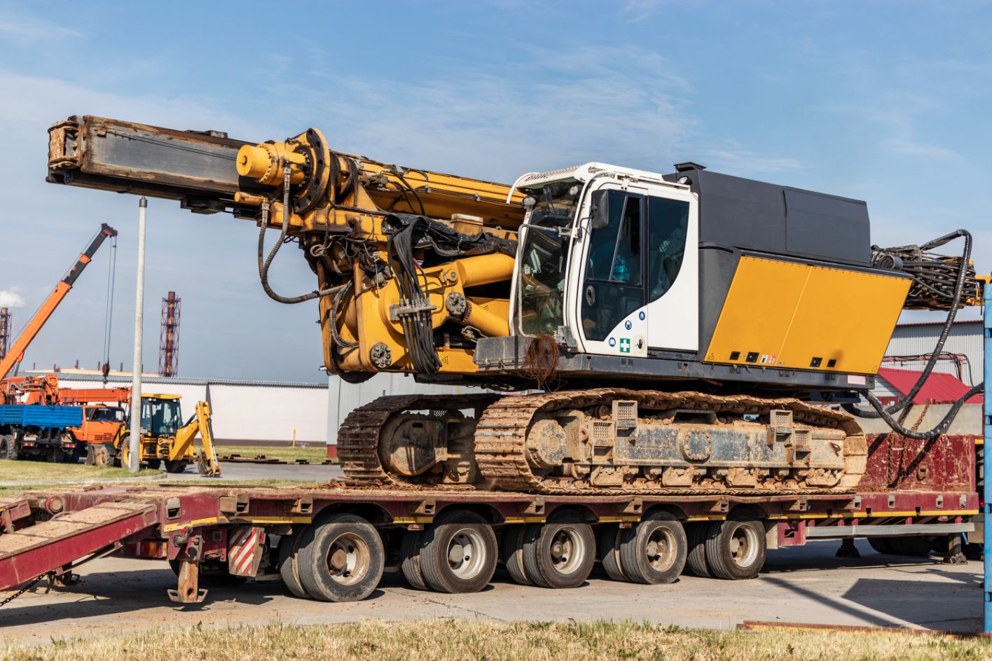 Verladung eines Bohrgeräts für die Installation von Bohrpfählen auf eine Schleppbahn für den Transport zum Einsatzort - leistungsstarke Baumaschinenpfahlgründung